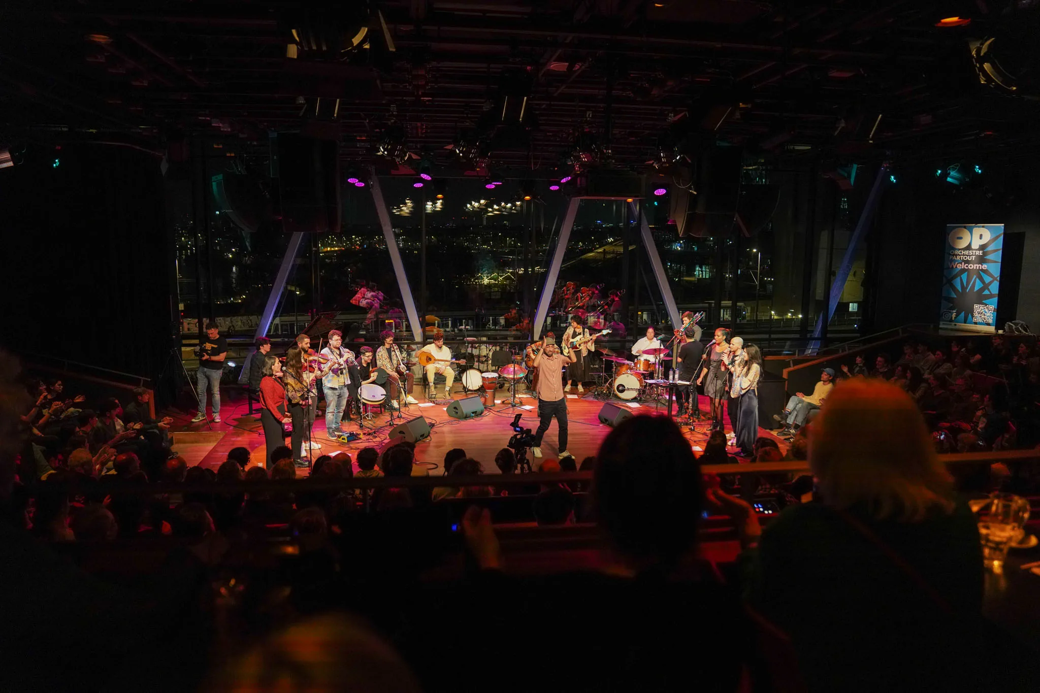 Concert met groot ensemble op het podium, gezien vanuit het publiek