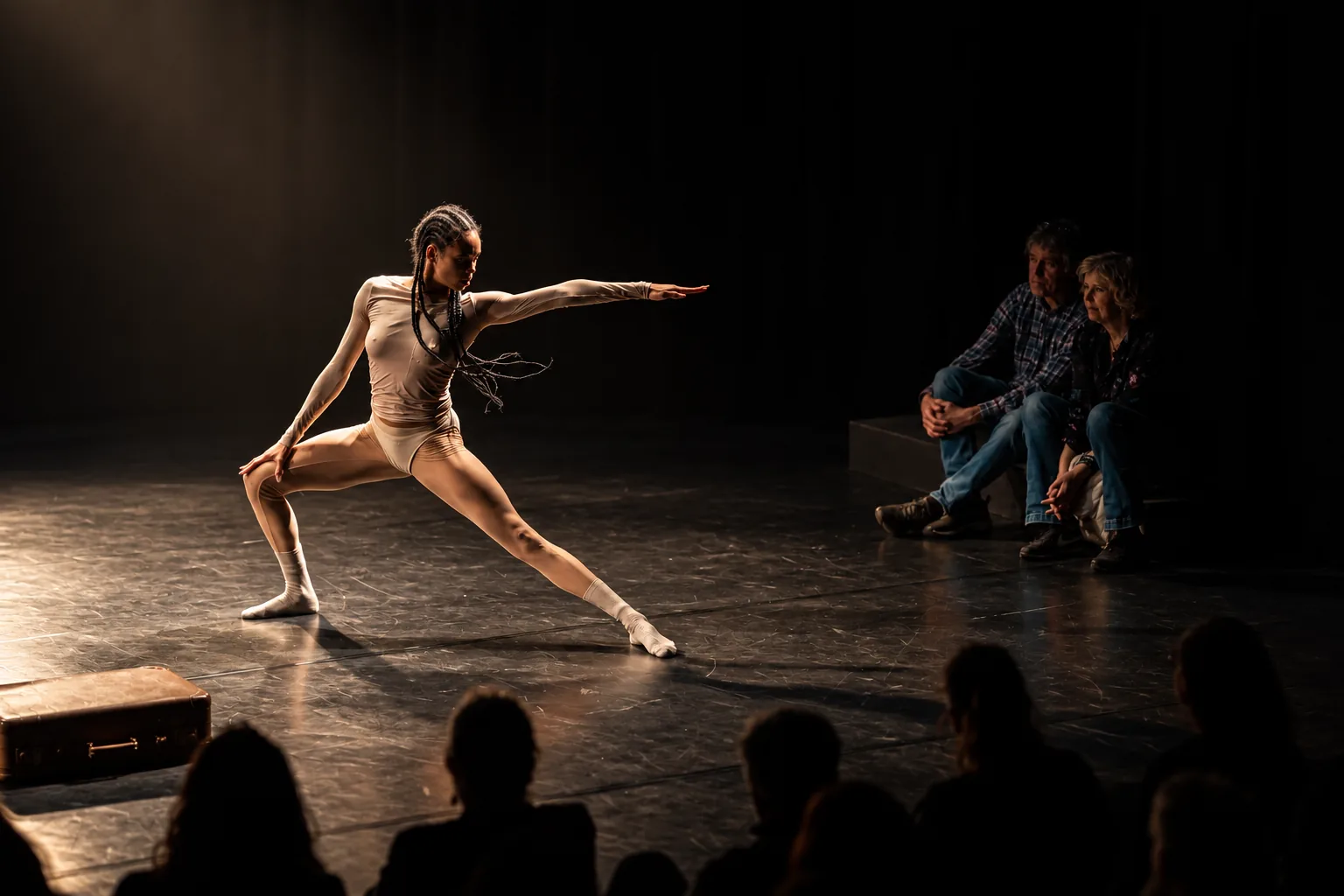 Danseres in beweging op een donker podium met toeschouwers